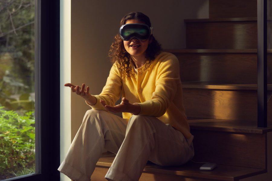 Woman interacting with another individual while wearing Apple AR/VR headset.